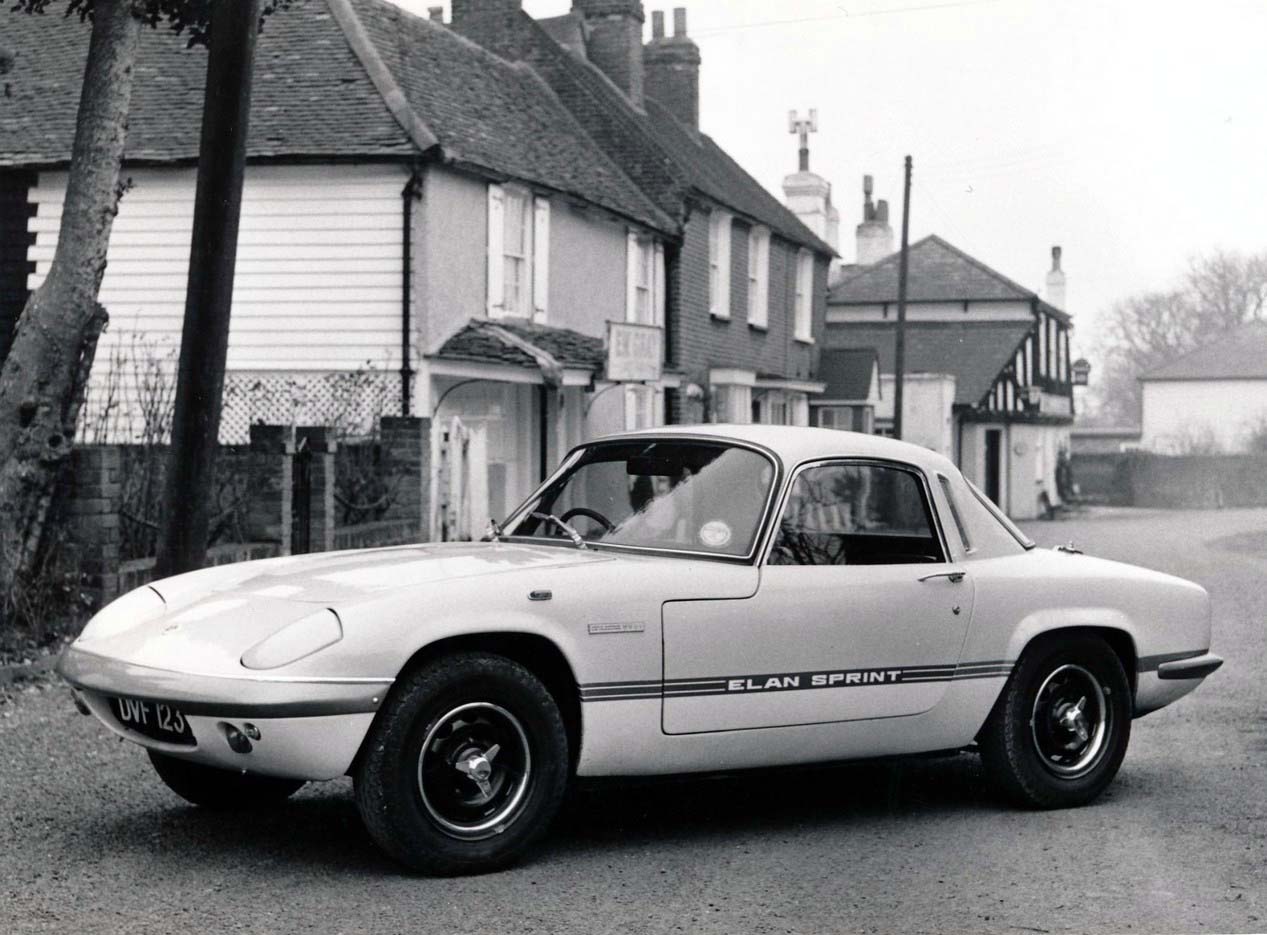 Una foto d'epoca che ritrae una Lotus Elan Sprint con cerchi neri in un paesino inglese