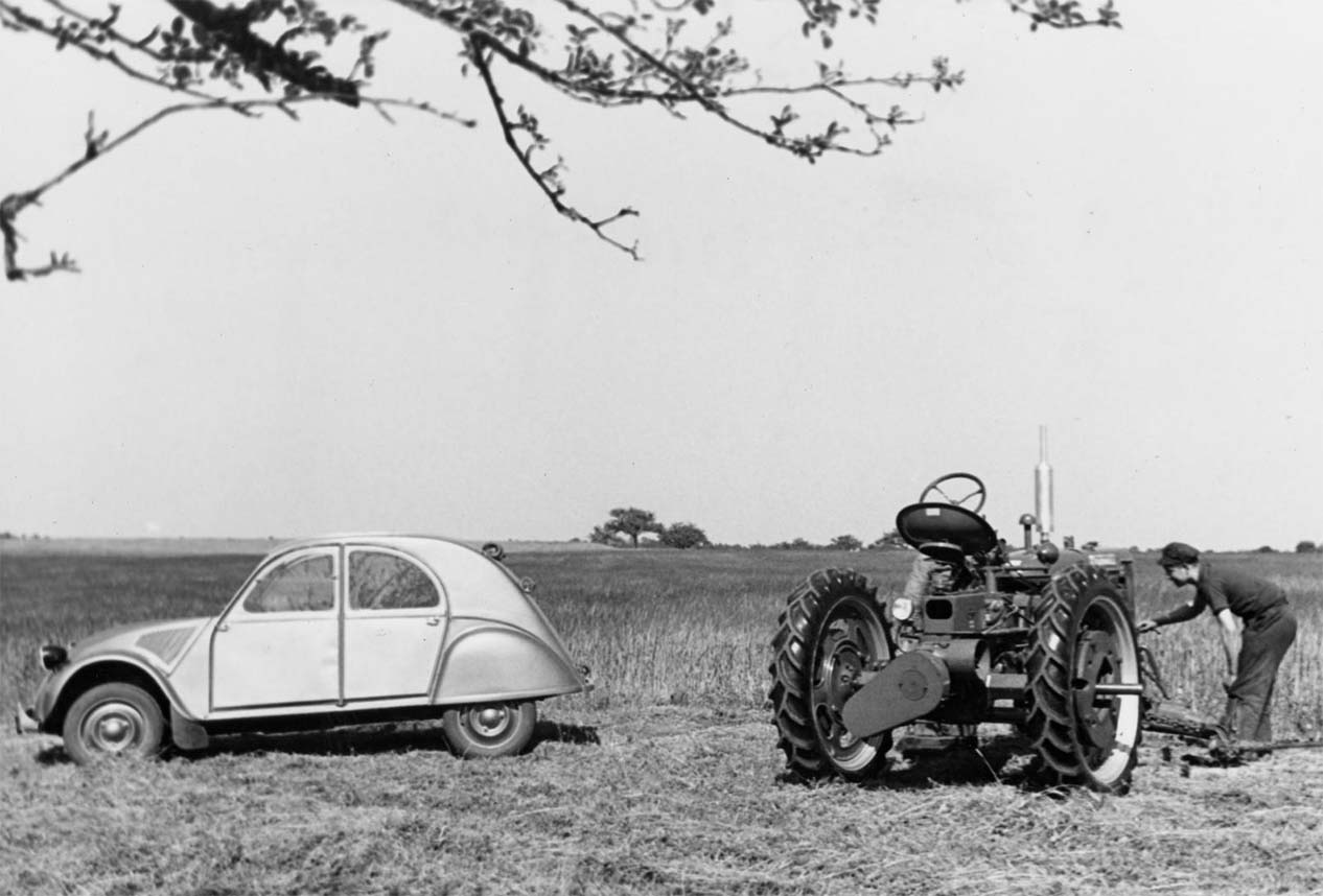 la citroen 2cv prima serie in un campo di grano con un trattore al lato